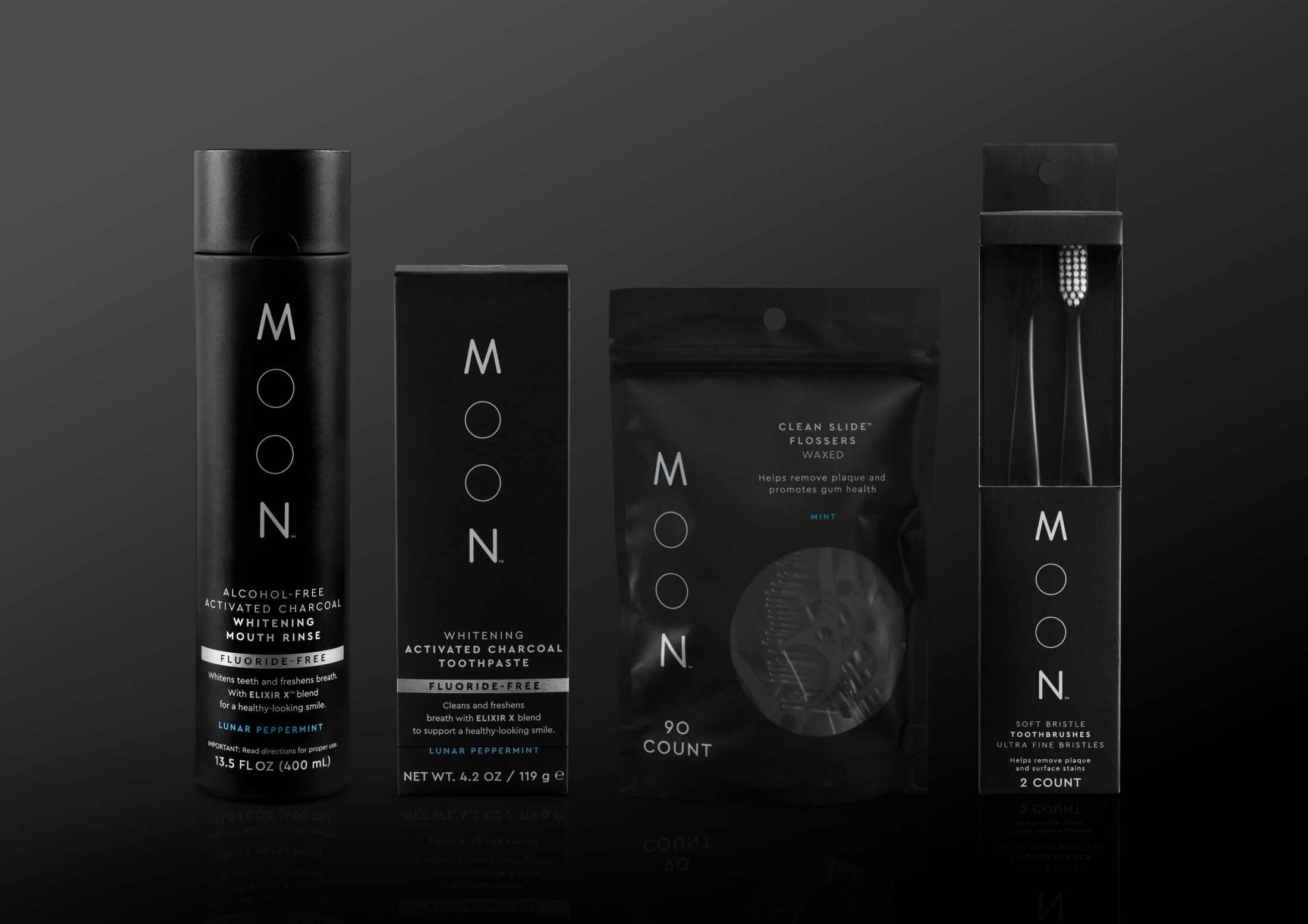 Moon Oral Care lineup of 4 products - Alcohol-Free Activated Charcoal Whitening Mouth Rinse, Whitening Activated Charcoal Toothpaste, Clean Slide™ Flossers, Soft Bristle Toothbrushes 2 pack. Packaging is black with typographic logo of "MOON" written vertically in silver. Products are photographed on a black surface.