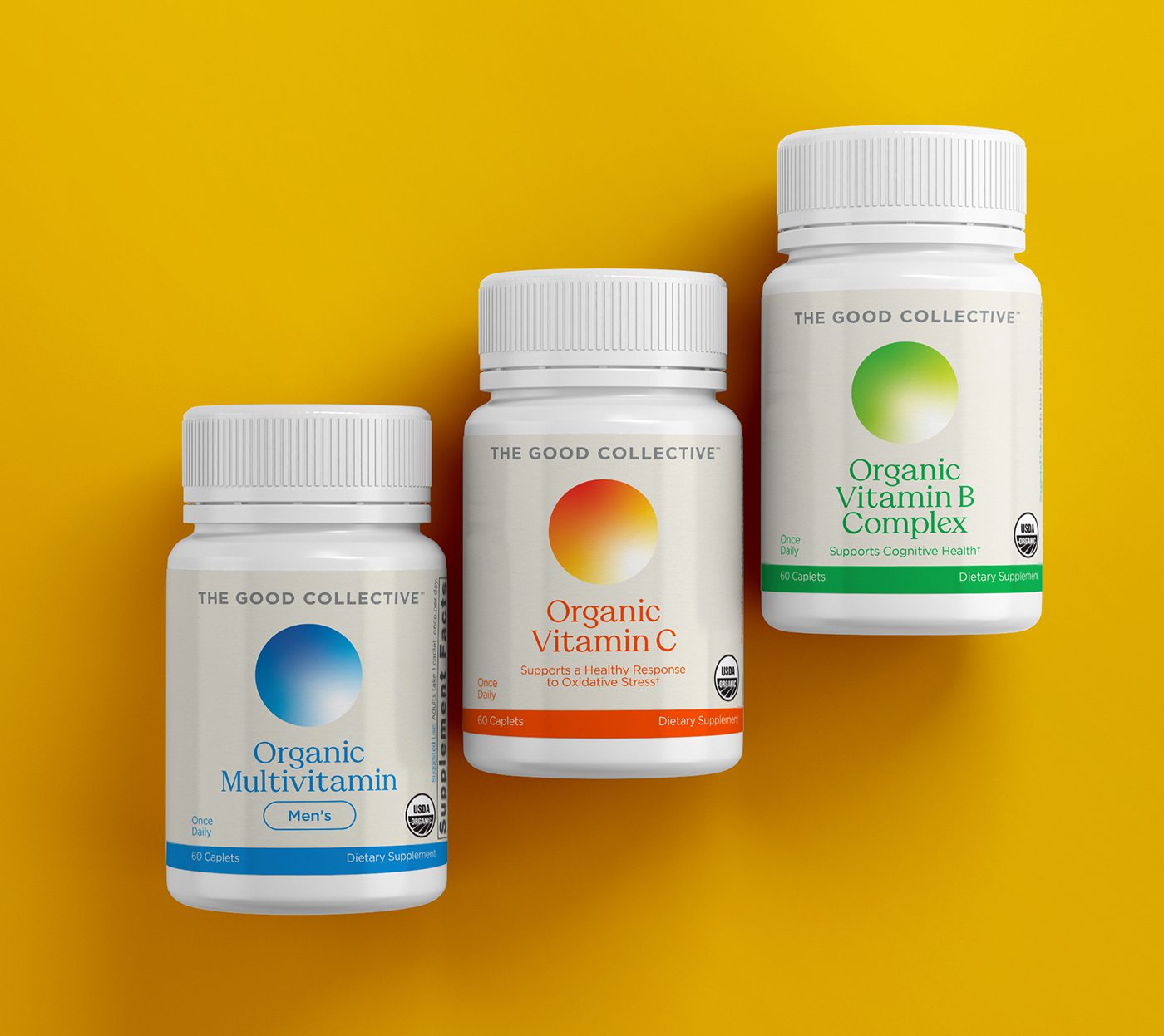 Overhead view of three The Good Collective vitamin bottles laid out in a staggered line over a yellow background. From left to right, Organic Men's Multivitamin, Organic Vitamin C, and Organic B Complex.